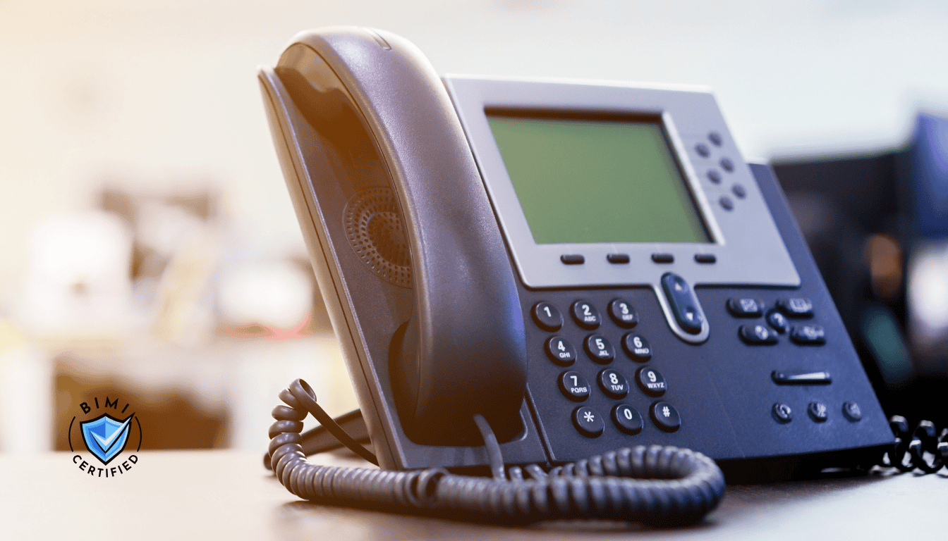 Modernus telefonas ant stalo laukia BIMI patikros skambučio